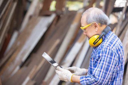 Male carpenter in a construction workshop, using a digital tabletの写真素材
