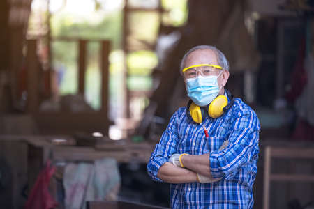 A mature carpenter standing confidently in his workshopの写真素材