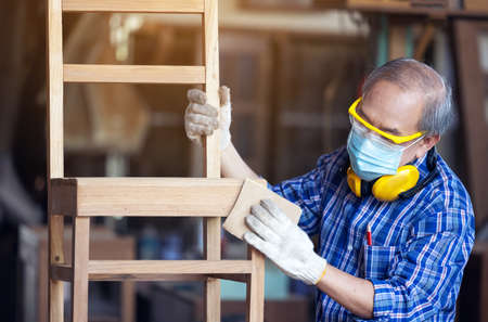 Carpenter, Senior man sanding wooden fence in workplace using work toolの写真素材