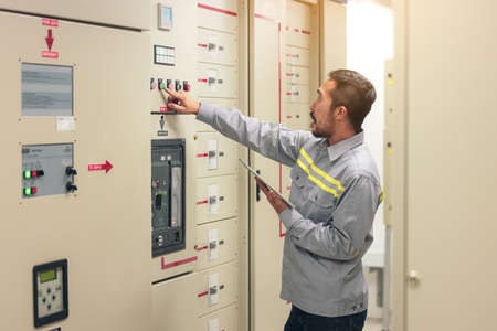 Close up hand of engineer or electrician man working check the electrical system with tablet at...