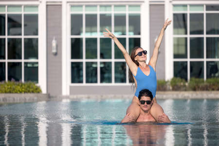 Cheerful couple swimming in a pool on vacation time enjoys