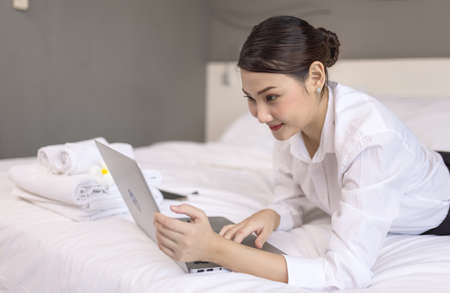 Young pretty woman working with laptop on the bed, Watching news, reading for exams, social network chat, internet surfing conceptの写真素材