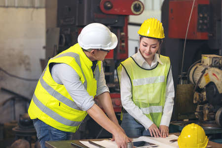 Contractor and engineer with blueprints discuss at a modern construction site, Engineers in...