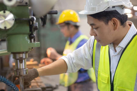 Two workers in production plant as team discussing, industrial scene in background, working together manufacturing activitiesの写真素材