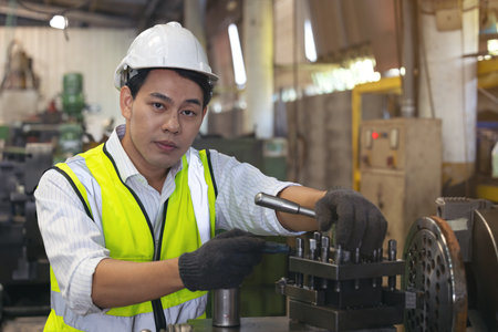 A worker in glasses standing near industrial equipment and verifies production. man operating machine in the factoryの写真素材