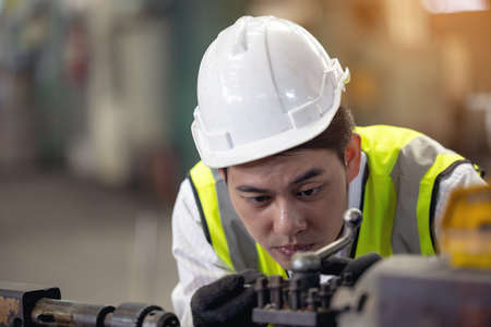 A worker in glasses standing near industrial equipment and verifies production. man operating machine in the factoryの写真素材