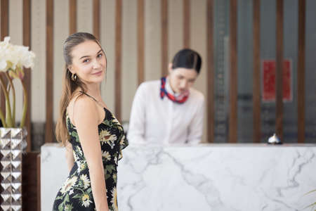 Portrait of female guest with baggage waiting to check in the hotel, happy travel lifestyle conceptの写真素材
