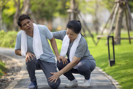 Asian elderly or senior man accident falling down on floor in the park while running exercise have...