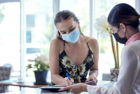 Receptionist hands over a passport to a tourist at te front desk and reception of a hostelの写真素材