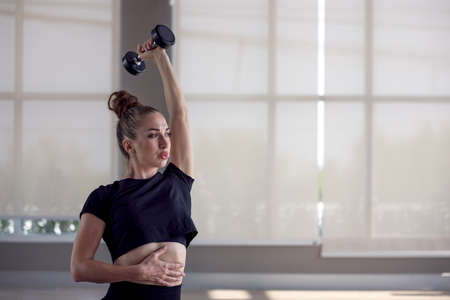 Fitness Sporty woman does the exercises with dumbbells, Strength and motivation.