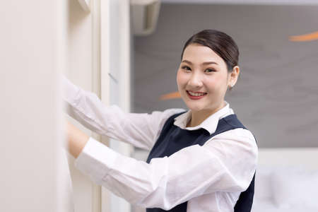 Smiling maid with White bathrobe with hanger in wardrobe, The concept of the hotel businessの写真素材