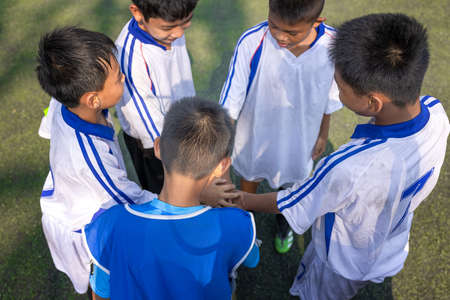View from below of young boy soccer players bringing hands together before gameの写真素材