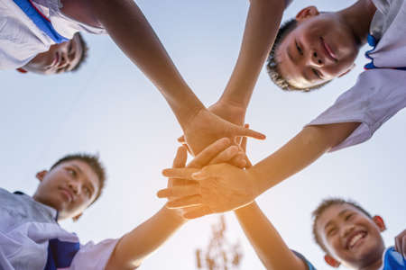 View from below of young boy soccer players bringing hands together before gameの写真素材