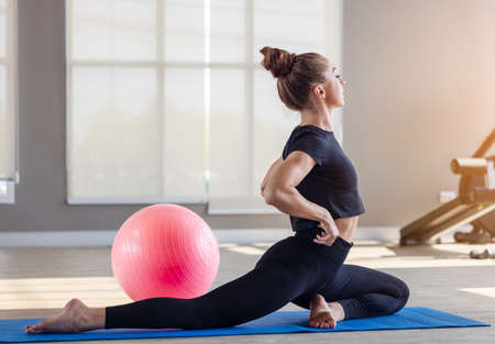Woman in an athletic look with aerobic exercise stretching loose, Young sporty woman stretching sit...