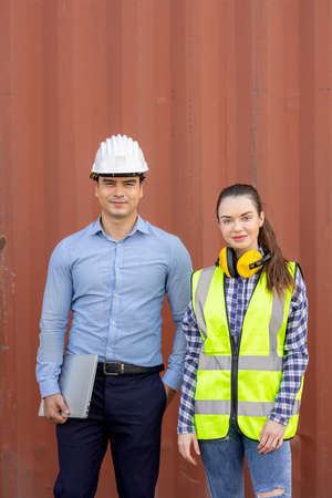 Confident engineers portrait in uniforms standing in front of the containers. Logistics and shipping. Professional occupation.の写真素材