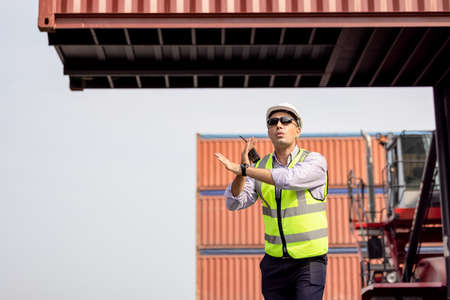 Man Using Walkie Talkie At Container Terminal, Industrial worker is controlling container loading
