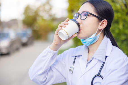 Portrait of tired exhausted nurse or doctor having a coffee break outside in the morning. COVID-19, Coronavirus pandemic.の写真素材