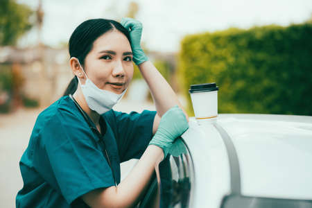 Portrait of tired exhausted nurse or doctor having a coffee break outside in the morning.の写真素材