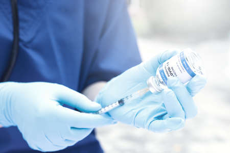 Female doctor with a stethoscope on shoulder holding syringe and COVID-19 vaccine. Healthcare And Medical concept.の写真素材