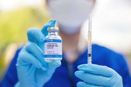 Female doctor with a stethoscope on shoulder holding syringe and COVID-19 vaccine. Healthcare And Medical concept.の写真素材