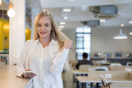 Smiling woman with cell phone at working spaceの写真素材