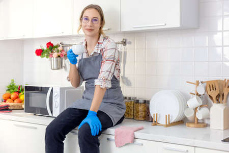 young pretty stylish woman holding white mug at white kitchen after clenching, Young woman relaxing,の写真素材