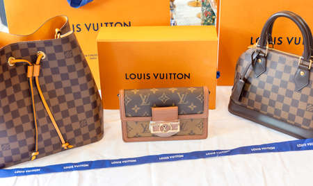 July 26, 2021: Nakhon Prathom, THAILAND, On the table is a Louis Vuitton bag, as well as another generic handbag brand. Louis Vuitton is a luxury fashion house that specializes in leather items.のeditorial素材