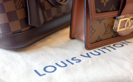 July 26, 2021: Nakhon Prathom, THAILAND, On the table is a Louis Vuitton bag, as well as another generic handbag brand. Louis Vuitton is a luxury fashion house that specializes in leather items.のeditorial素材