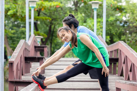 A fitness couple stretches in the park. In the morning, a young man and a young woman exercise...
