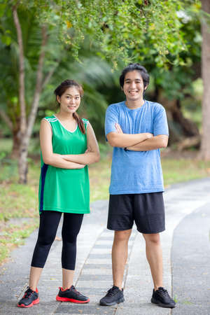 In the park, a young couple of runners pose for a portrait. Sport and love as a conceptの写真素材