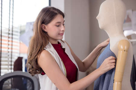 A model is used by a fashion designer to try on new designer garments. At work, a woman entrepreneur in her fabric business is designing new clothing for a fashion designer.の写真素材