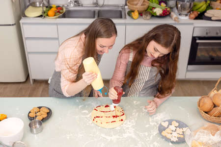 In the kitchen at home, a playful mother and daughter yell while making pizza dough.の写真素材