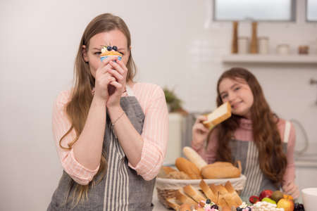 American mother and daughter holding cupcakes and smiling at each otherの写真素材