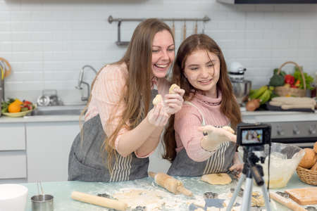 With a live digital camera in the kitchen, mother and daughter smile and have fun while preparing...