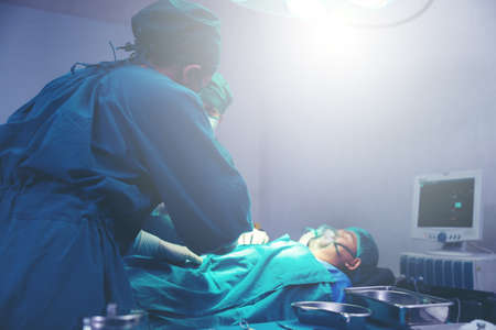 Inside a sophisticated operating room, an Asian doctor does surgery.