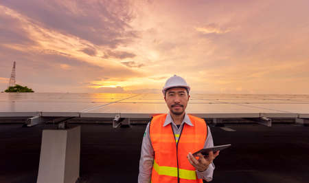 Engineers use a tablet to work on roof inspection and maintenance in a solar power plant, which...