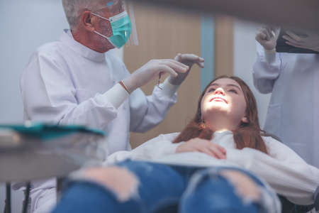 Teeth checkup at the dentist, doctor performing dental treatment on a woman and a girl in the dentist's officeの写真素材