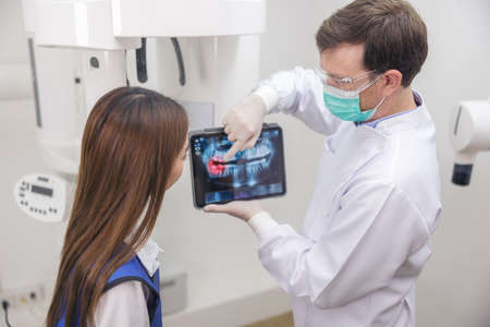 A dentist uses a tablet to show a patient her x-ray.の写真素材