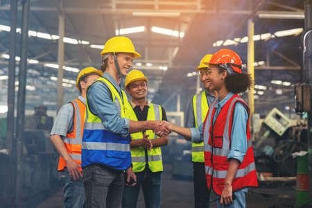 A group of industry workers and engineers of various races enjoy working in a heavy plant and stand together with a pleasant smile. portraitの写真素材