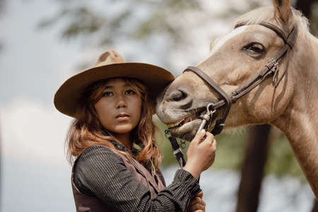 At sunset, a beautiful sensual girl and her horse go through the woods. Horses are adored by girls.