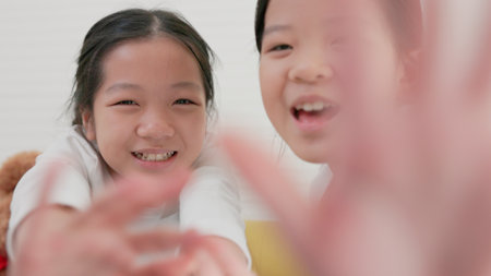 Smiling tiny girls and a happy family holiday and childhood concept Children are having a good time at home, sitting on the sofa in the living room.の写真素材