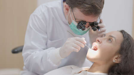 In the clinic, a dentist cleans the teeth of a patient.の写真素材