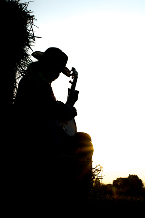 A young man playing the banjo The straw in the field The golden sun, warm happily. Beautiful shadows.の写真素材