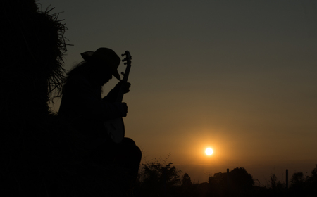 A young man playing the banjo the straw in the field The golden sun, warm happily. Beautiful shadows.の写真素材