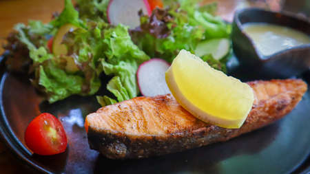 Grilled salmon fillet, slow cooked steak with lemon on top served with mixed green salad, fresh...