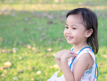 Positive charming 4 years old cute baby Asian girl, little preschooler child smiling and looking to the left.の写真素材