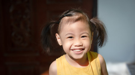 Positive charming 4 years old cute baby Asian girl, little preschooler child smiling and looking at camera.の写真素材
