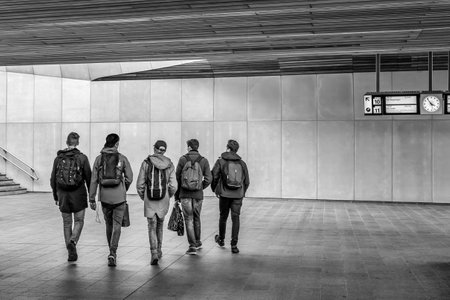 Five male persons with backpacks on their back walking to the exit in black and white.の写真素材