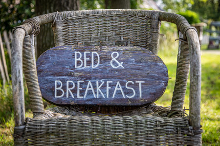 Wooden sign on an old reed chair outdoors with bed and breakfastの写真素材