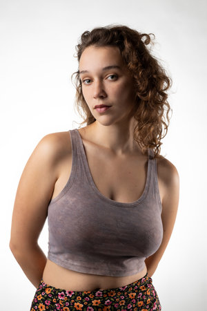 Studio portrait of a confident young lady with hands behind her back and white backgroundの写真素材